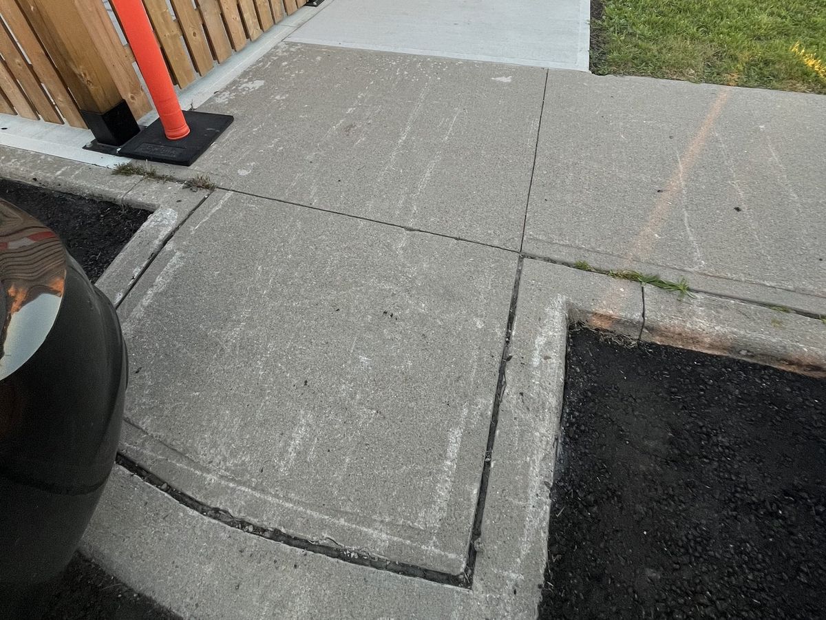 Concrete sidewalk curb transition with no tactile indicator, before the retrofit