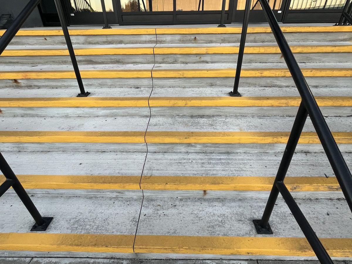 Concrete entrance stairs with painted yellow tread edges and no anti-slip surface, before the retrofit
